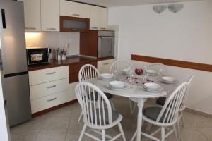 a kitchen with a white table and four chairs at Apartman Marijela in Vela Luka