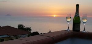una bottiglia di vino e due bicchieri su un tavolo con il tramonto di New ! Panorama Sea View Tropea Zambrone con Piscina Privata a Zambrone