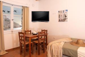 a room with a table and chairs and a tv on the wall at Cheronissos View in Sifnos