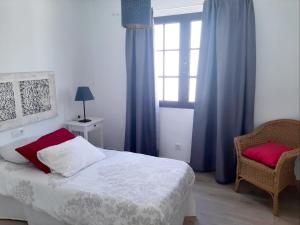 ein Schlafzimmer mit einem Bett, einem Stuhl und einem Fenster in der Unterkunft Casa Diana in Playa Honda