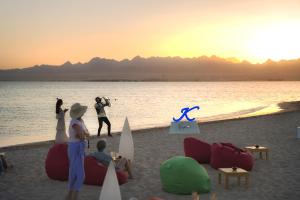a group of people standing on a beach with the ocean at Kempinski Hotel Soma Bay in Hurghada