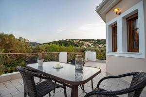 a patio with a table and chairs on a balcony at Luxury Rustic Villa Mountain View in Lefkada Town