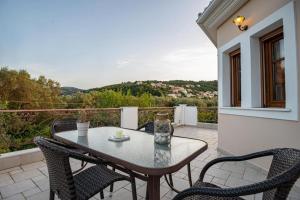 un patio con tavolo e sedie sul balcone. di Luxury Rustic Villa Mountain View a Città di Lefkada