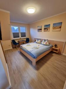 a bedroom with a bed and two chairs in it at Hotel Pension Nordseewelle in Norddeich