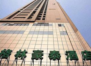 un grand bâtiment avec des chaises vertes devant lui dans l'établissement GreenTree Inn Jiangsu NanJing GuLou Business Hotel, à Nankin