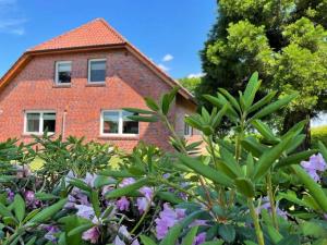 une maison en briques derrière un jardin de fleurs dans l'établissement Ferienwohnung an der Ems 75100, à Westoverledingen