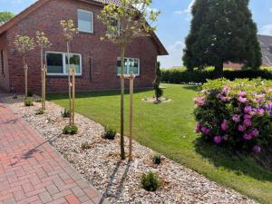 un jardin avec des arbres et des fleurs devant une maison dans l'établissement Ferienwohnung an der Ems 75100, à Westoverledingen