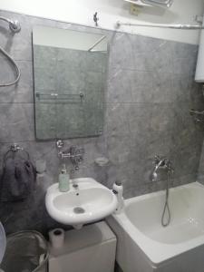 a bathroom with a sink and a tub and a mirror at Apartman Maja in Bijeljina
