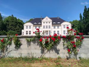 a white house with red roses on a wall at Schloß Wichmannsdorf in Kröpelin