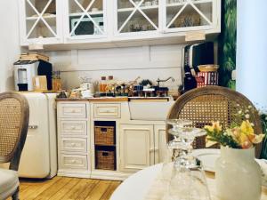 a kitchen with white cabinets and a table and a refrigerator at Epoca Home in Cosenza