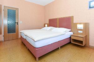 a bedroom with a large bed and a door at Hotel-Pension Altes Siel in Bensersiel