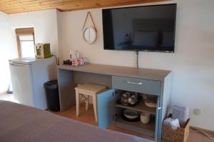 a bedroom with a desk with a television on the wall at Guest House Lambovi in Nesebar