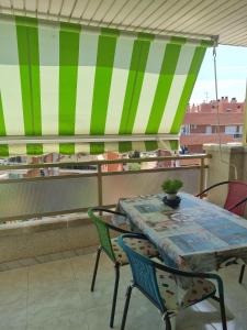 uma mesa e cadeiras numa varanda com um dossel verde e branco em COSTA DAURADA APARTAMENTS - Paraisol em Salou