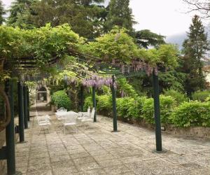 un jardín con pérgola con sillas y vides púrpuras en Il Loft di Villa al Parco, en Sala Baganza