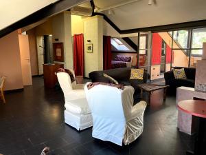 sala de estar con 2 sillas blancas y sofá en Il Loft di Villa al Parco, en Sala Baganza