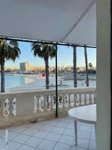 a balcony with a view of a beach and palm trees at Angolina Apartments 130 in Birżebbuġa