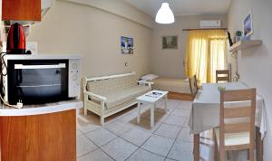 a living room with a couch and a tv and a table at Sourada Studios in Mytilene