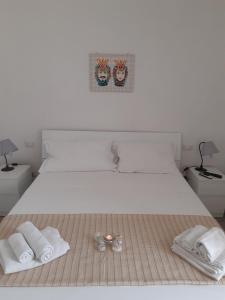 Una cama blanca con dos toallas y dos vasos. en Fronte Mare en Avola
