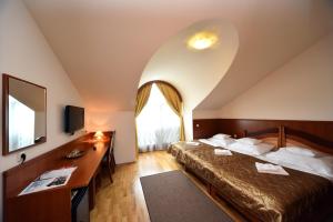Pokój hotelowy z łóżkiem i biurkiem w obiekcie Hotel Kumánia w mieście Kisújszállás