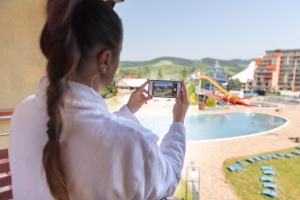 a girl taking a picture of a pool with her cell phone at Apartmán Aqua Bešeňová in Bešeňová