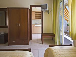 1 dormitorio con 2 camas y armario con TV en Ikaros Apartments, en Paralia Katerinis