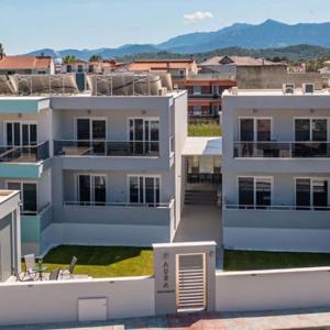 un grande edificio bianco con montagne sullo sfondo di AURA APARTMENTS a Keramotí