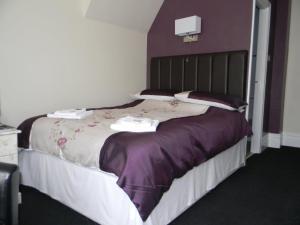 a bedroom with a large bed with purple sheets and pillows at Devon Guest House in Blackpool