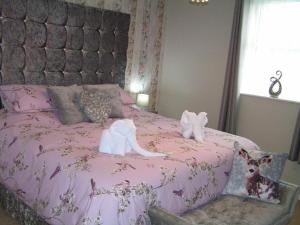 Una cama rosa con dos animales de peluche. en Devon Guest House, en Blackpool