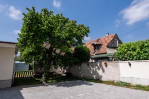 ein Haus mit einem Baum vor einem Zaun in der Unterkunft Hello Apartman in Sopron