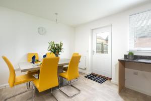 a dining room with a table and yellow chairs at KVM - Thorpe House in Peterborough