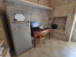 a kitchen with a refrigerator and a desk with a computer at Dimora Assuntina Martano in Martano