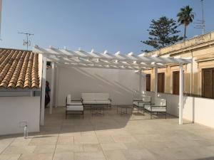 a white pergola with chairs and tables on a patio at Amate Case by Ortigia Apartments in Siracusa