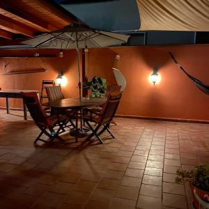 Villa il Vento e il Mare في Selargius: طاولة وكراسي مع مظلة في الغرفة