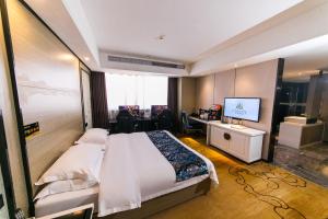 een slaapkamer met een bed, een bureau en een televisie bij Cheng Bao Hotel Shantou Mixc Branch in Shantou