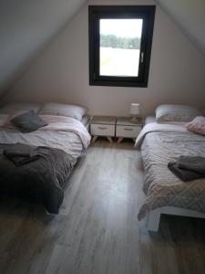 a attic bedroom with two beds and a window at Domek letniskowy na Kaszubach, Borowy Młyn, jezioro Gwiazda in Borowy Młyn