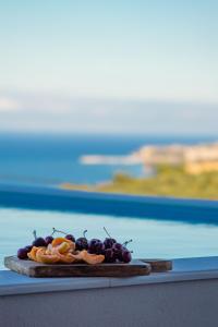 a plate of grapes and oranges on a table at Georgianna's suite with private pool , 'greysuite' in Kómpoi