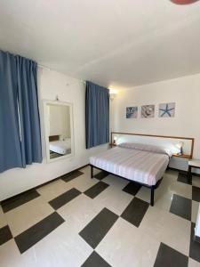 een slaapkamer met een bed en een spiegel en een geruite vloer bij Villa Bianca in Peschici