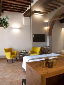 a bedroom with a bed and two yellow chairs at La Corte Segreta in Montepulciano