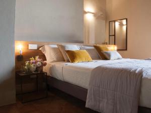 モンテプルチャーノにあるLa Corte Segretaのベッドルーム1室(白いシーツと黄色い枕の大型ベッド1台付)