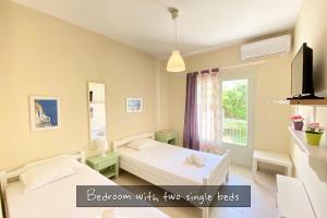 a bedroom with two single beds and a window at Afitos Beach Apartments in Afitos