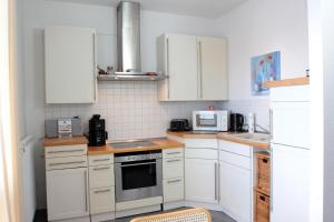 una cocina con armarios blancos y electrodomésticos blancos en Ferienwohnung-Bieberblick, en Greifswald
