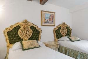 two beds in a room with gold and green headboards at Gondola Luxury - Campo Santi Filippo e Giacomo in Venice