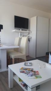 a living room with a white table and a tv at Ferienwohnung-Suedstrandflair in Burgtiefe auf Fehmarn 