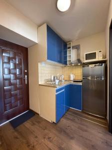 cocina con armarios azules y nevera de acero inoxidable en 02 Gdynia Centrum - Apartament Mieszkanie dla 2 os en Gdynia