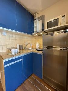 cocina con armarios azules y nevera de acero inoxidable en 02 Gdynia Centrum - Apartament Mieszkanie dla 2 os en Gdynia