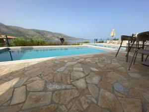 a stone patio with a pool and a table and chairs at Elia Luxury Suites in Plataria