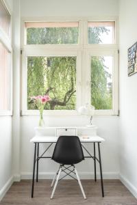 un escritorio blanco con una silla negra frente a una ventana en InnsbruckHomes at Botanical Garden en Innsbruck