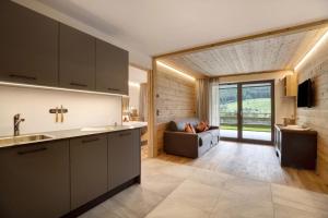 eine Küche und ein Wohnzimmer mit einem Sofa in der Unterkunft Archehof Hochzirm Lodge Anton in Sand in Taufers