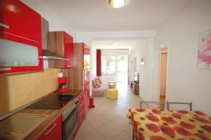 a kitchen with red cabinets and a living room at Apartment Blanka in Njivice