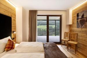 Schlafzimmer mit einem Bett und einer Glasschiebetür in der Unterkunft Archehof Hochzirm Lodge Anna in Sand in Taufers